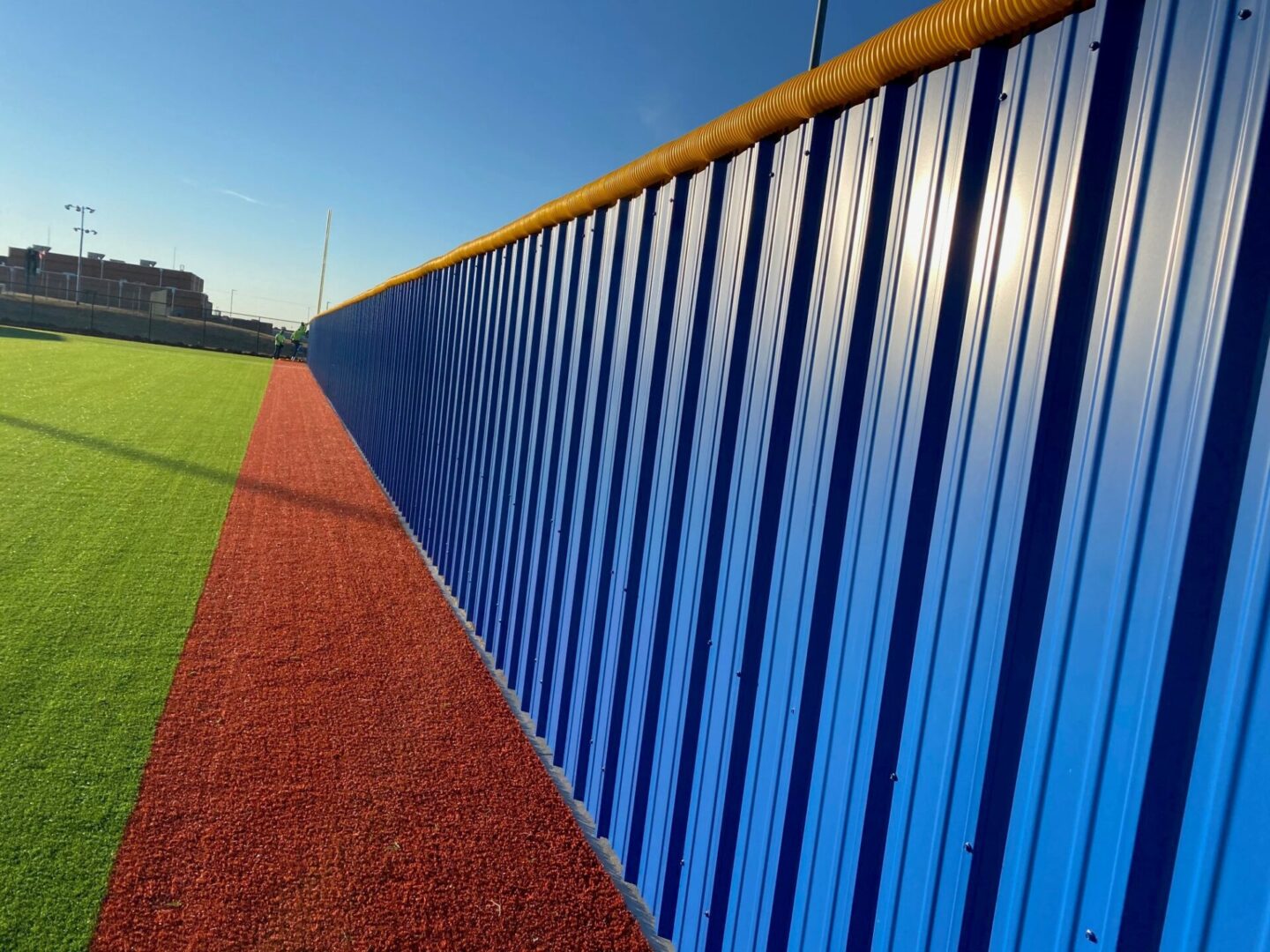 A baseball field with blue fence and red track.